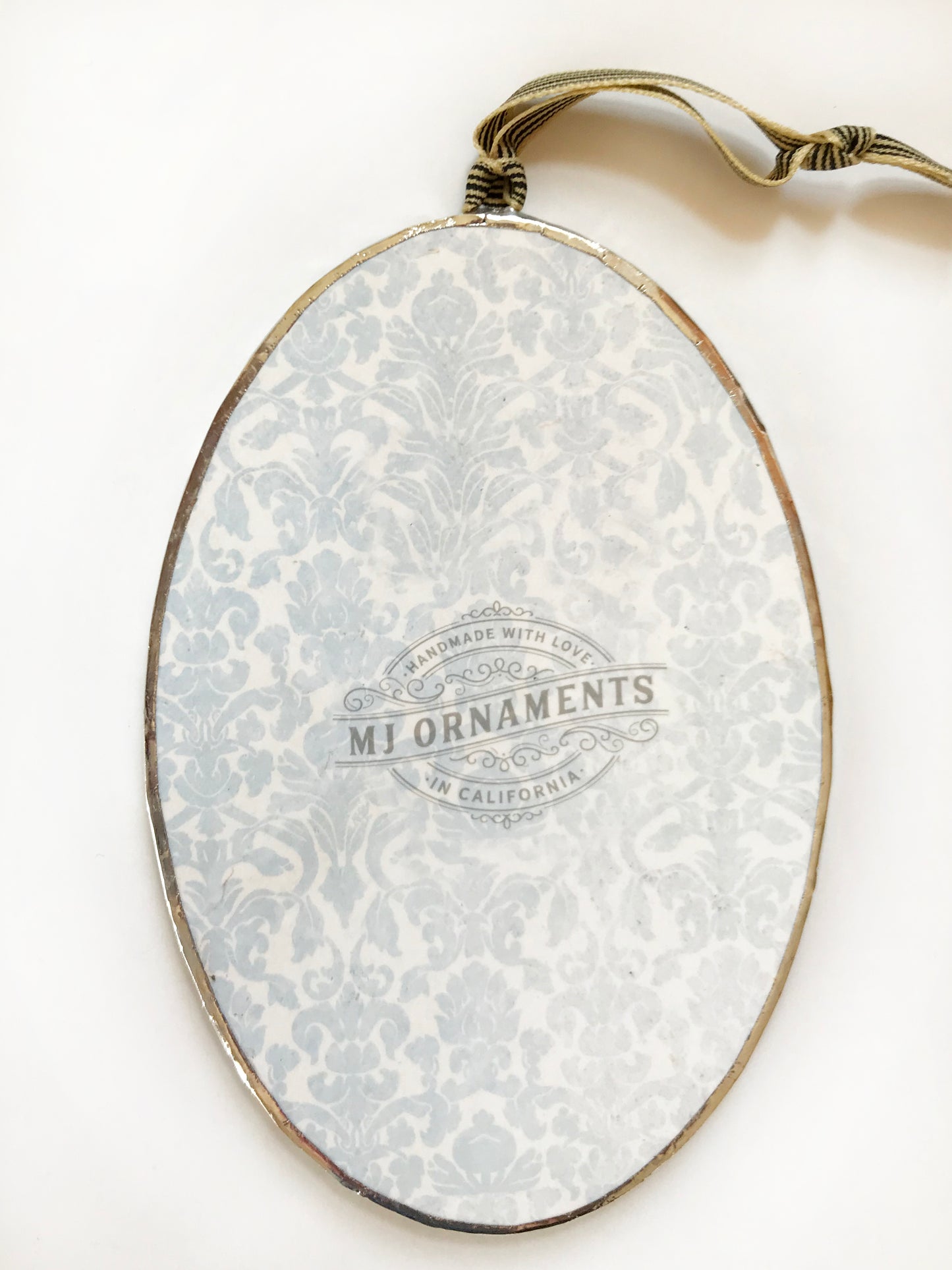 Decorative oval with floral pattern and 'MJ Ornaments' branding on a white background