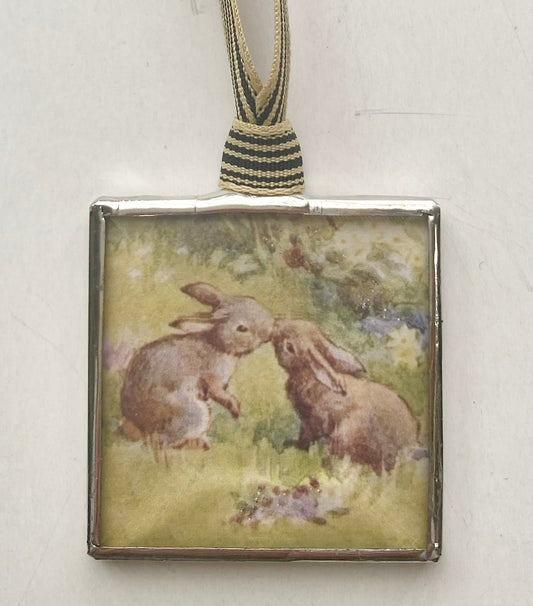 Decorative ornament with two rabbits on a grassy background