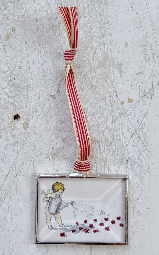 Decorative angel ornament with red and white striped ribbon on a textured surface