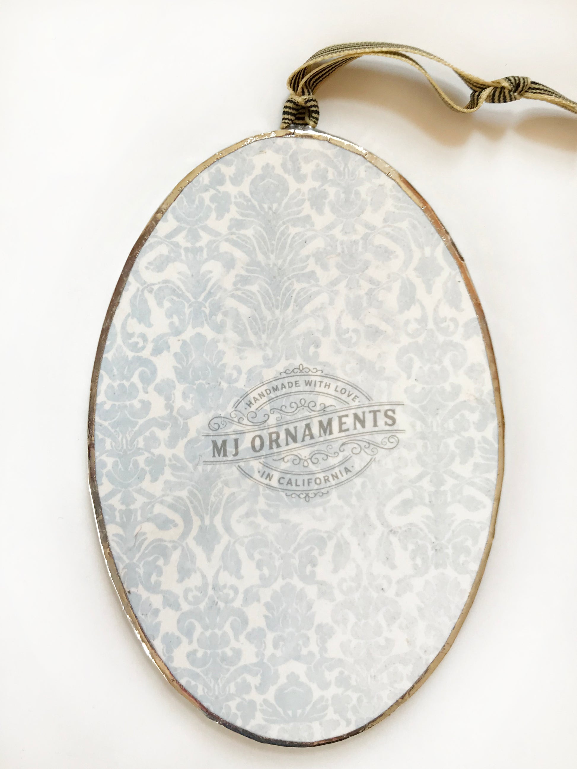 Decorative oval with floral pattern and 'MJ Ornaments' branding on a white background